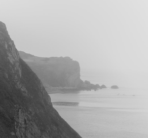 black and white photo of mountains and the ocean